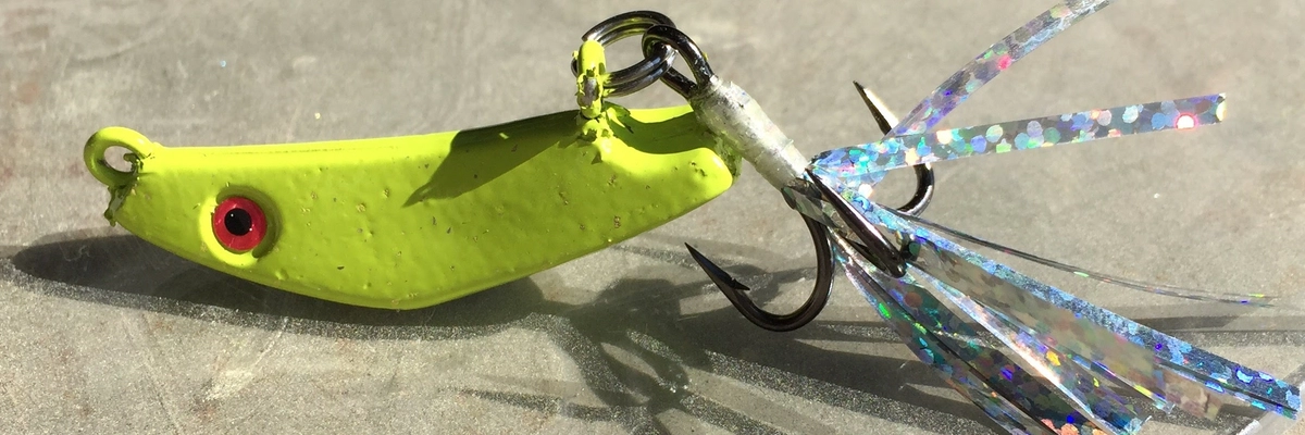 Chartreuse slab spoon with a flash-dressed treble hook for striper fishing.